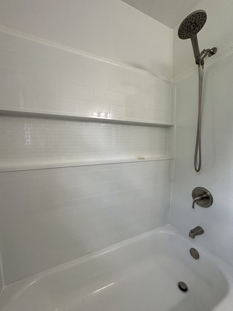 a white bathtub with a shower in a bathroom