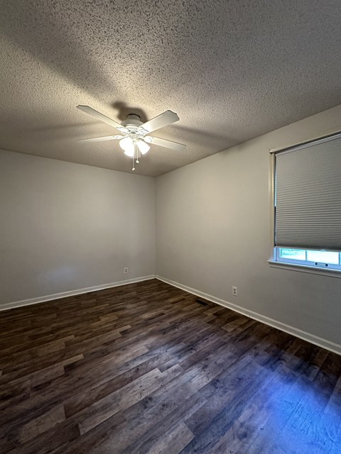 an empty living room with a ceiling fan and a window