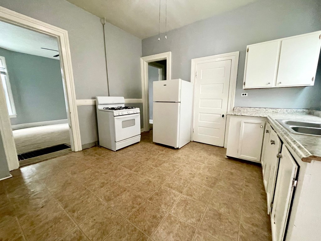 an empty kitchen with a stove refrigerator and sink