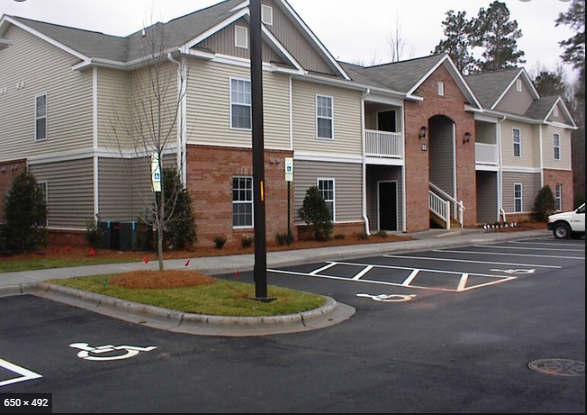 a parking lot in front of a row of apartment buildings