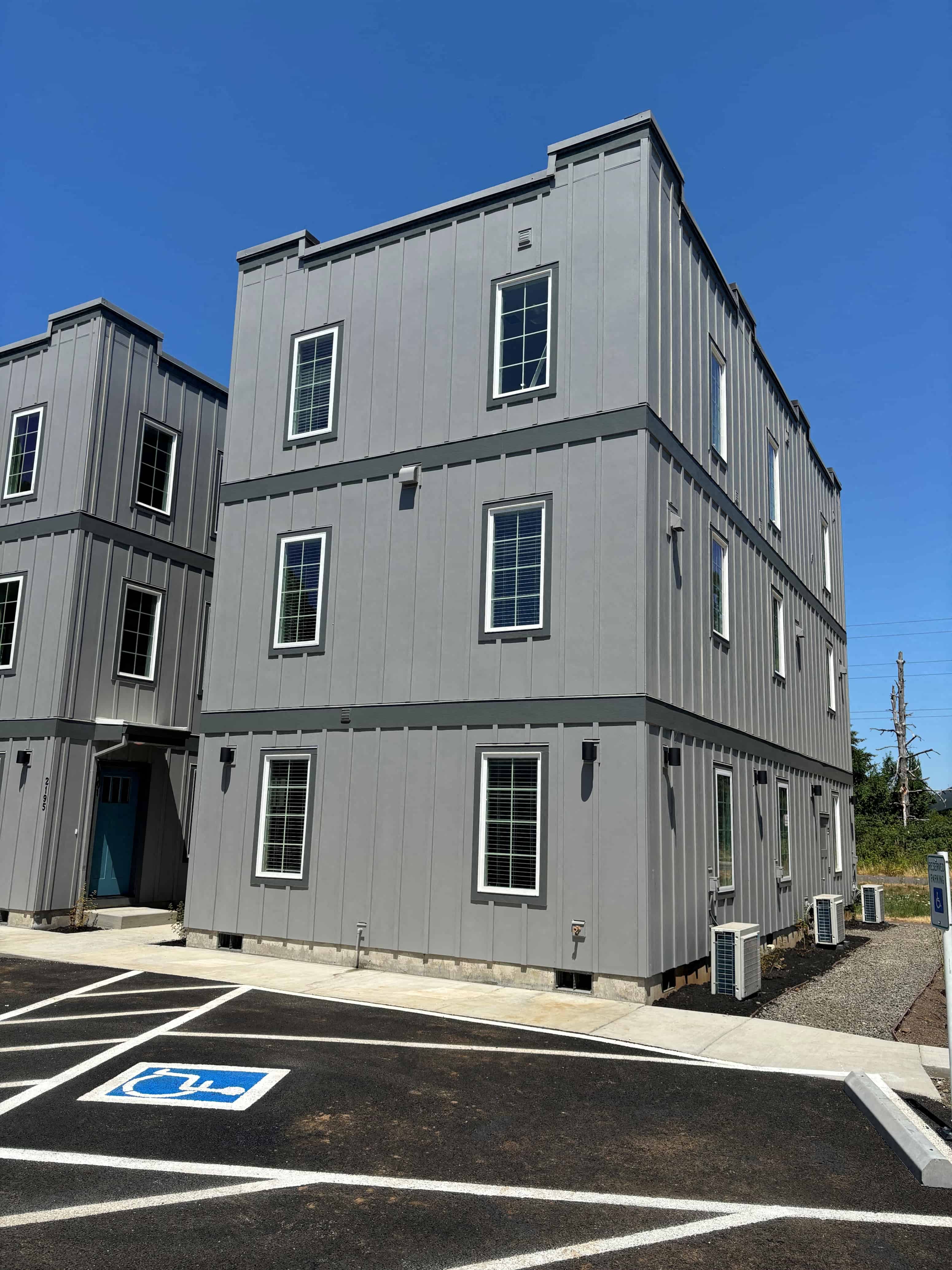 a gray building with a parking lot in front of it
