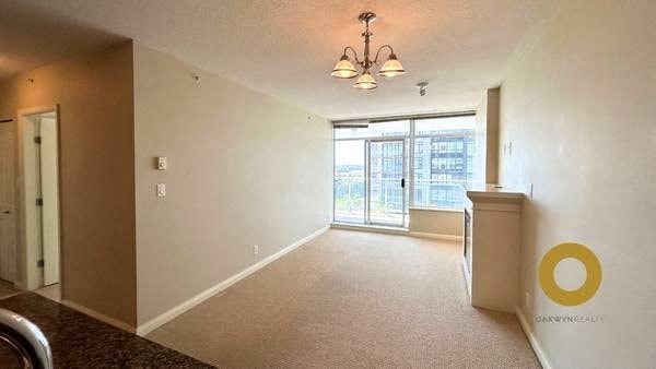 an empty living room with a large window and a kitchen