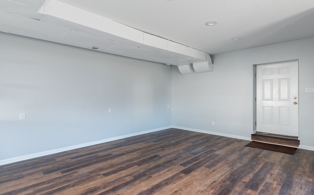 a living room with a white door and wood flooring
