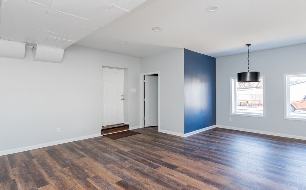 an empty living room with a blue wall and wood floors