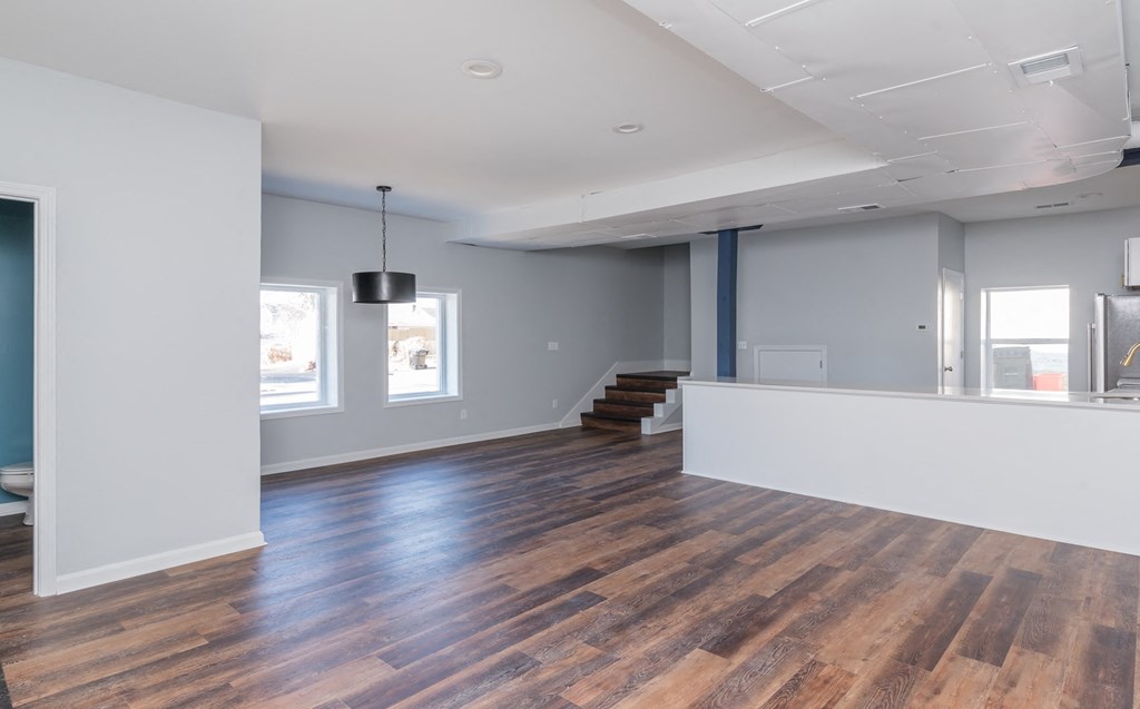an empty living room with wood floors and white walls
