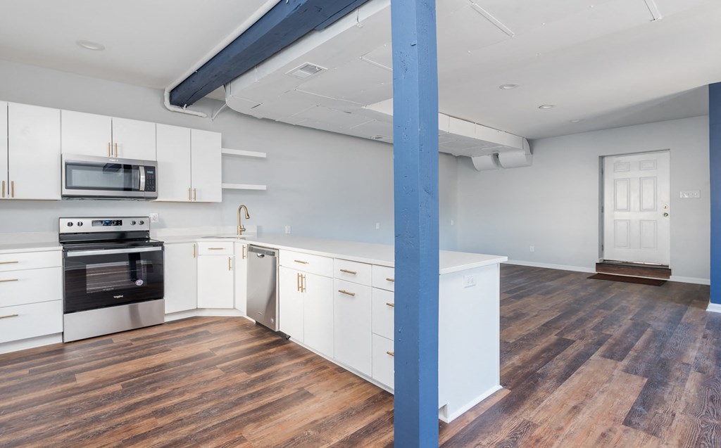 a large kitchen with white cabinets and a blue pillar