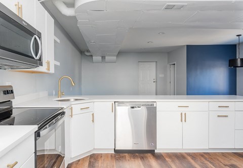a kitchen with white cabinets and stainless steel appliances and a blue wall