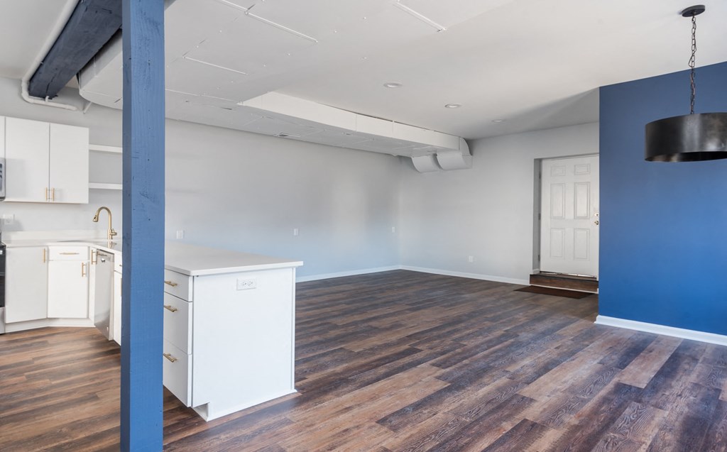 a living room with a blue accent wall and a kitchen with wood floors