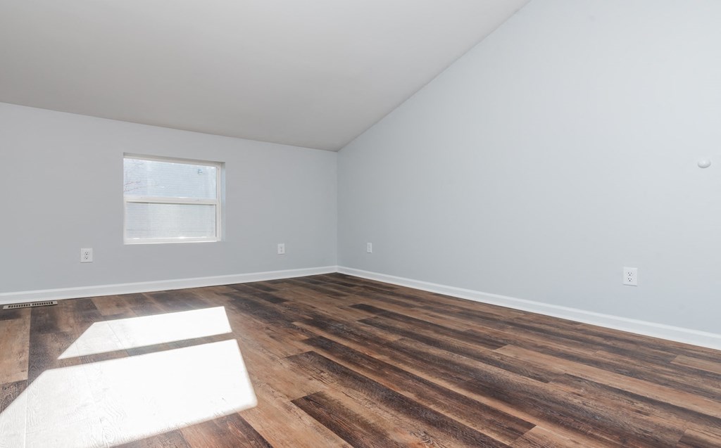 an empty room with wood flooring and a window