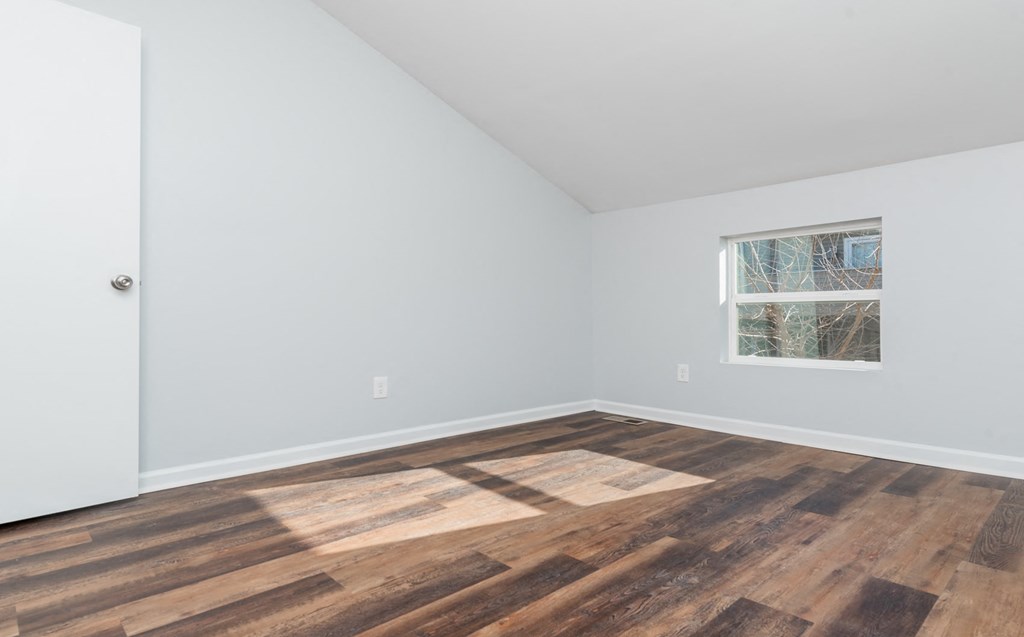 a room with wood floors and white walls and a window