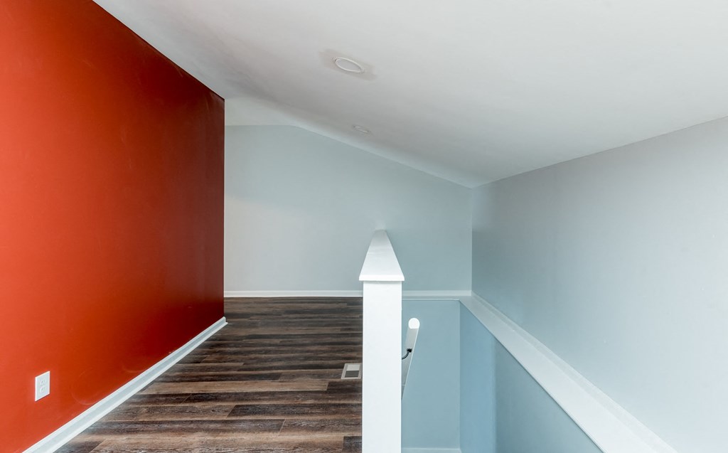 a hallway with a red wall and blue walls and a staircase