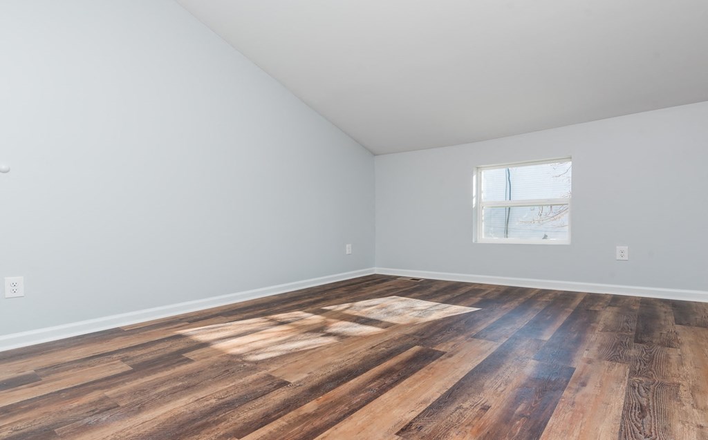 an empty room with wood floors and a window
