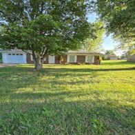 a house with a yard and a tree in front of it