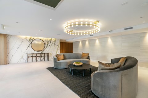 A modern living room with a grey sofa, a round table, and a hanging light fixture.