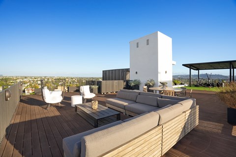 A white building with a wooden deck and outdoor furniture.