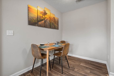 a dining area with a table and chairs and a painting on the wall