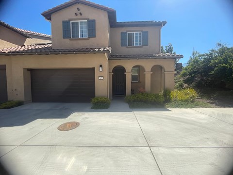 A house with a brown roof and tan walls with a garage door.