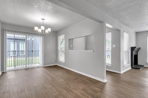 the living room and dining room of an apartment with wood flooring and a window
