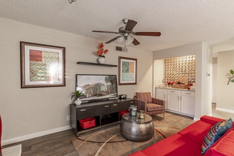 a living room with a red couch and a ceiling fan