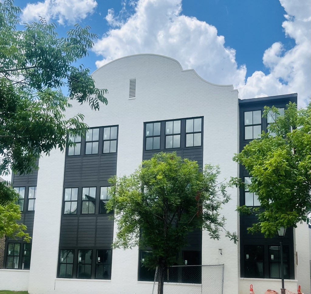 the exterior of a white building with trees in front of it