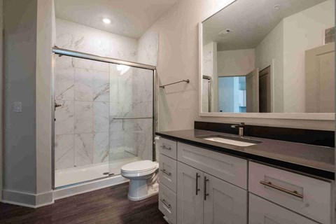 A bathroom with a marble shower and a toilet.