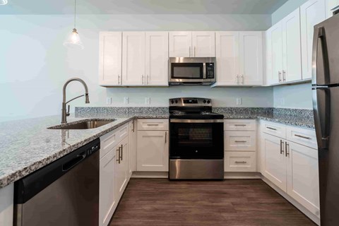 A kitchen with white cabinets and a black dishwasher.