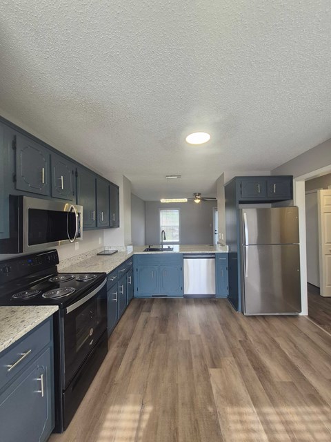 A kitchen with dark blue cabinets and stainless steel appliances.