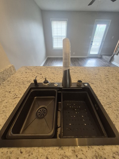 A kitchen sink with a faucet and a drain cover.