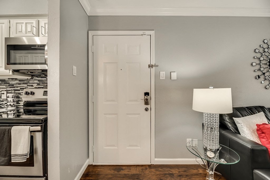a living room with a white door and a kitchen
