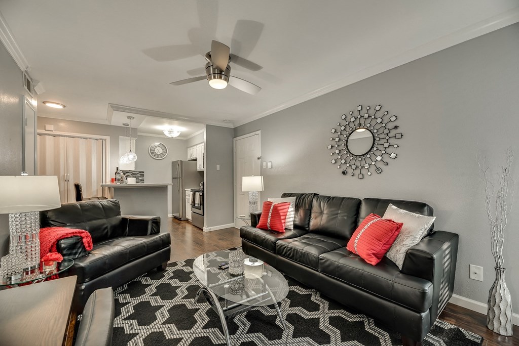 a living room with two leather couches and a glass coffee table