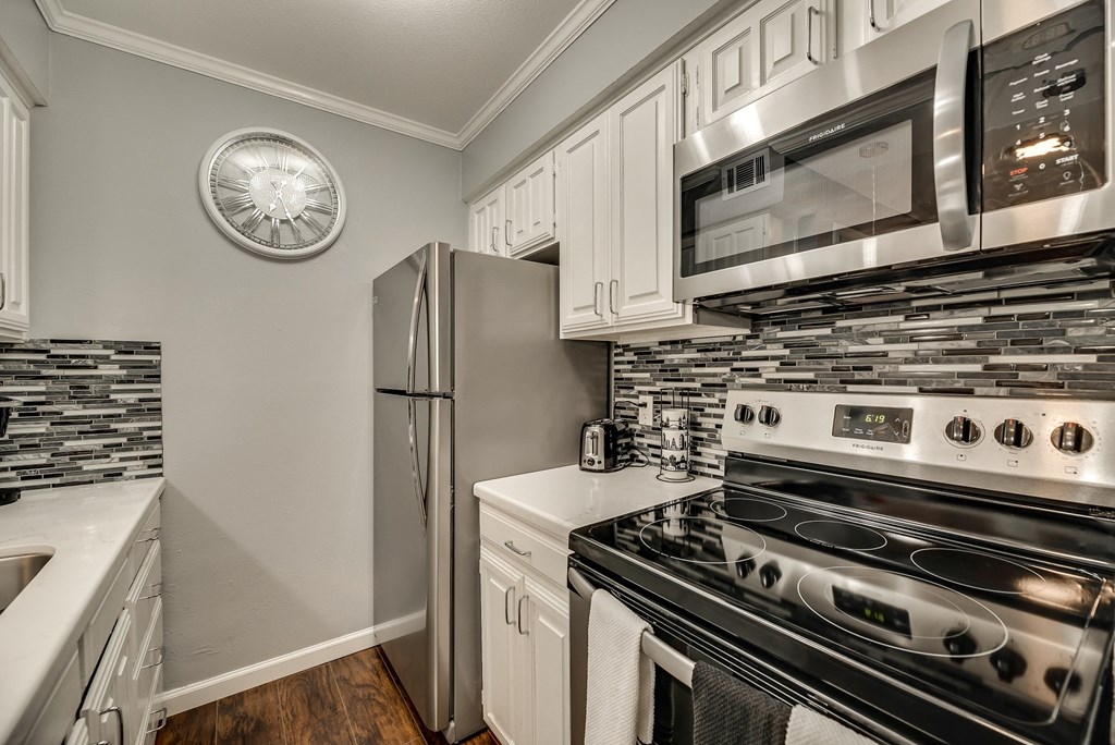 an updated kitchen with stainless steel appliances and white cabinets