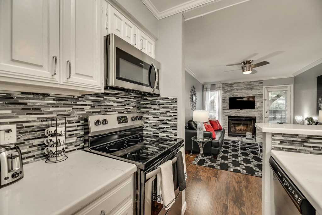 a kitchen with a stove and microwave and a living room with a fireplace