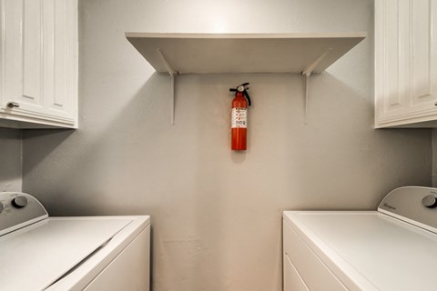 the laundry room has a extinguisher on the wall