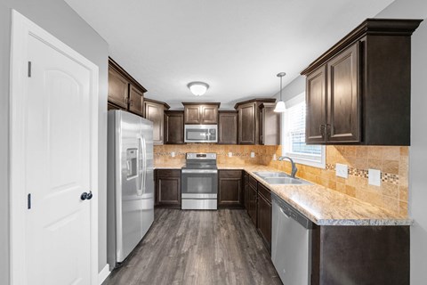 A kitchen with dark wood cabinets and a tiled backsplash.