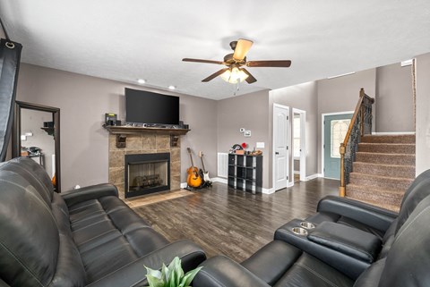 A living room with black leather couches and a fireplace.