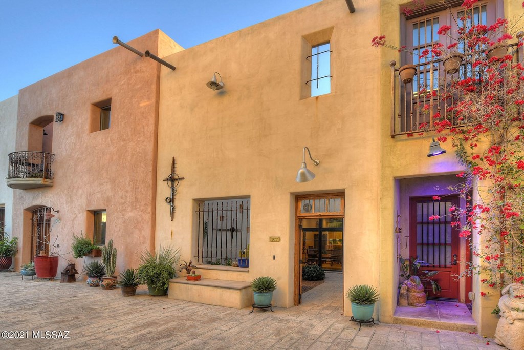 the front of the house has a courtyard and a red door