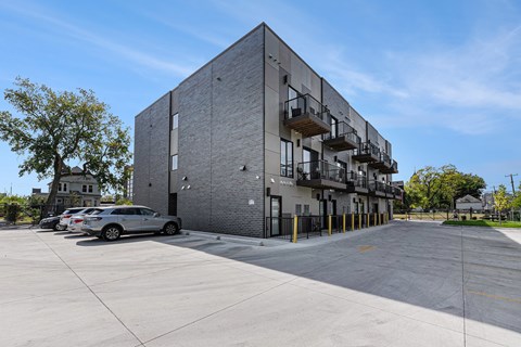 A grey building with a parking lot in front.