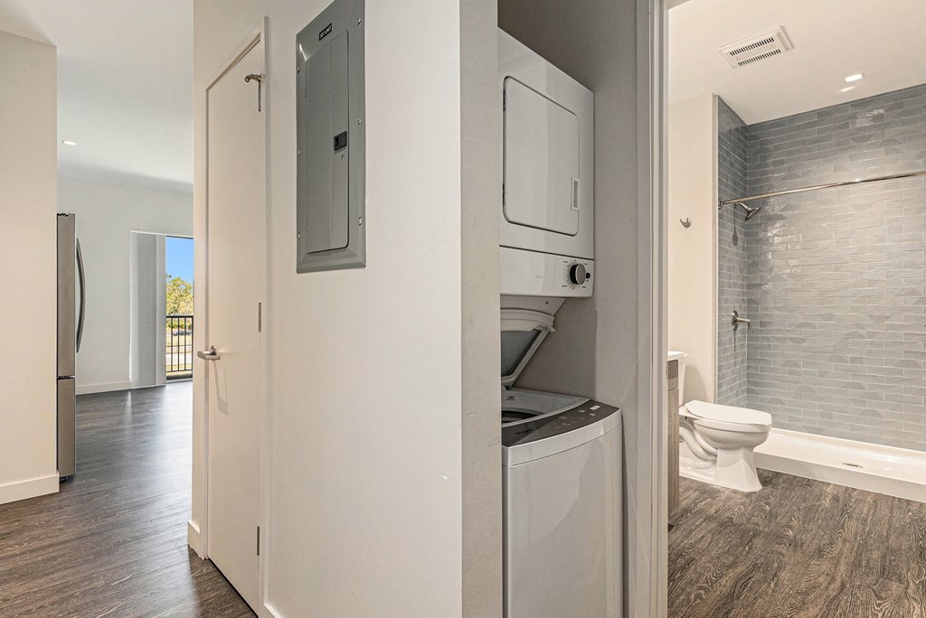 A modern bathroom with a washer and dryer built into the cabinetry.