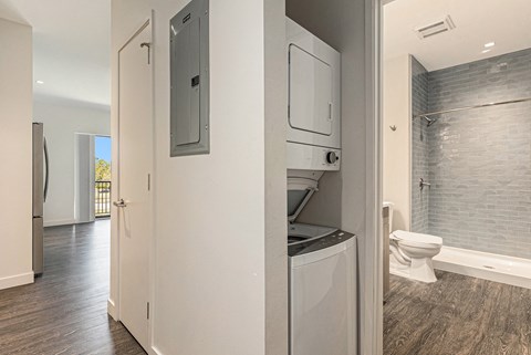 A modern bathroom with a washer and dryer built into the cabinetry.