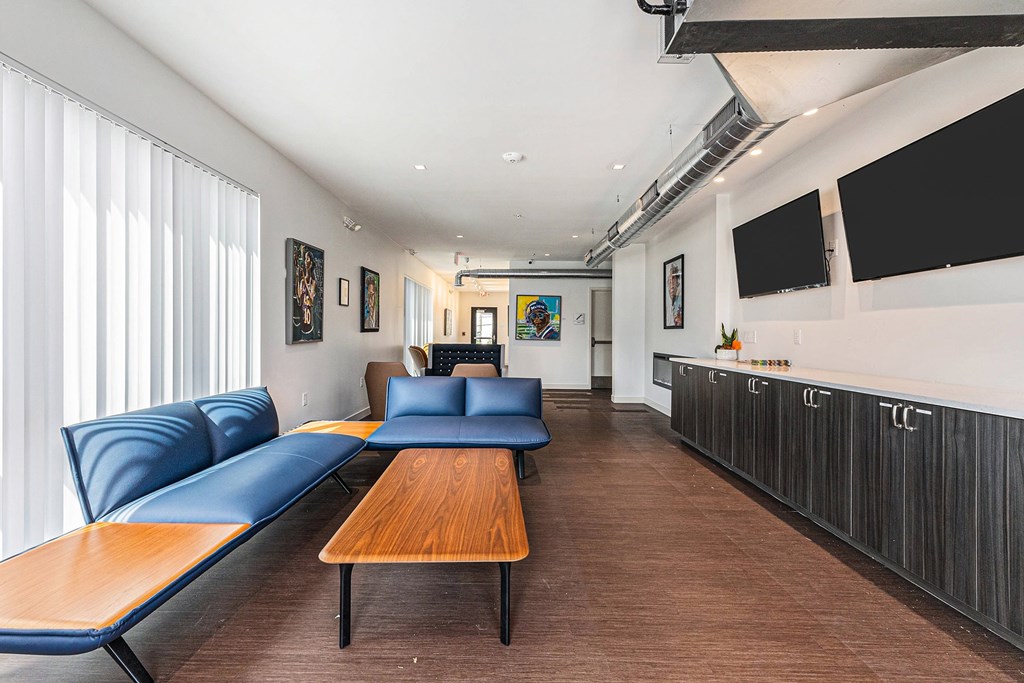 A modern living room with a long wooden table and blue couches.