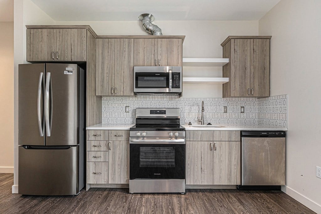 A kitchen with a refrigerator, oven, microwave, and dishwasher.
