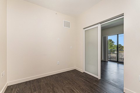A room with a sliding glass door leading to a balcony.