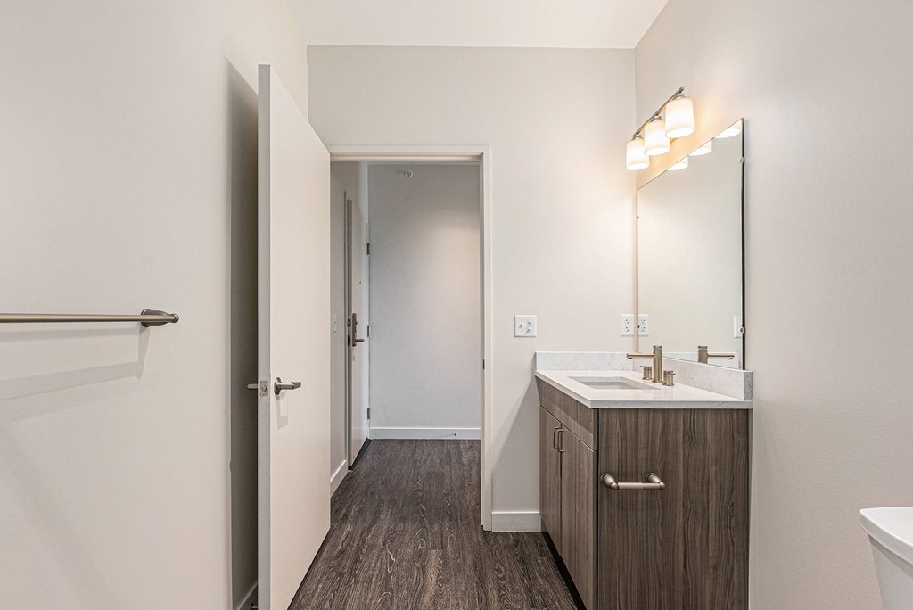 A bathroom with a sink, mirror, and wooden floors.