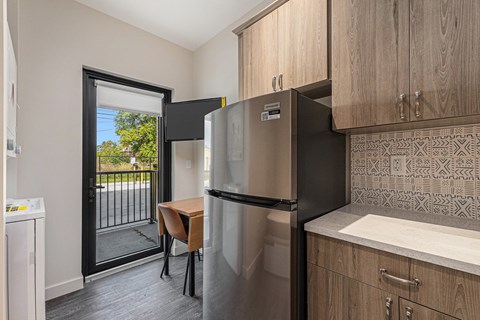 A kitchen with a refrigerator, a washing machine, and a table.