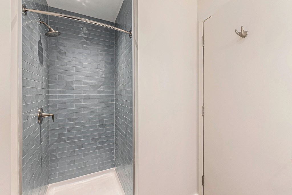 A shower area with a glass door and a white door.