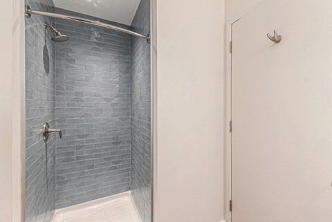 A shower area with a glass door and a white door.