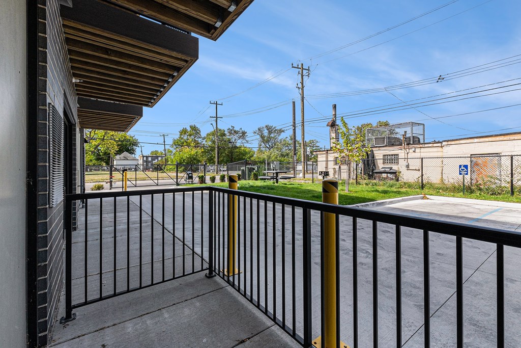A balcony with a black railing and a yellow post.