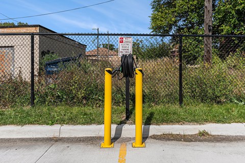 Two yellow bollards in front of a fence with a sign on it.