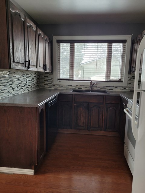 A kitchen with wooden cabinets and a white dishwasher.