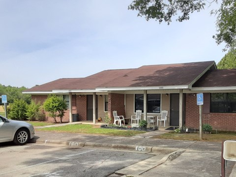 a parking lot in front of a brick building with tables and chairs